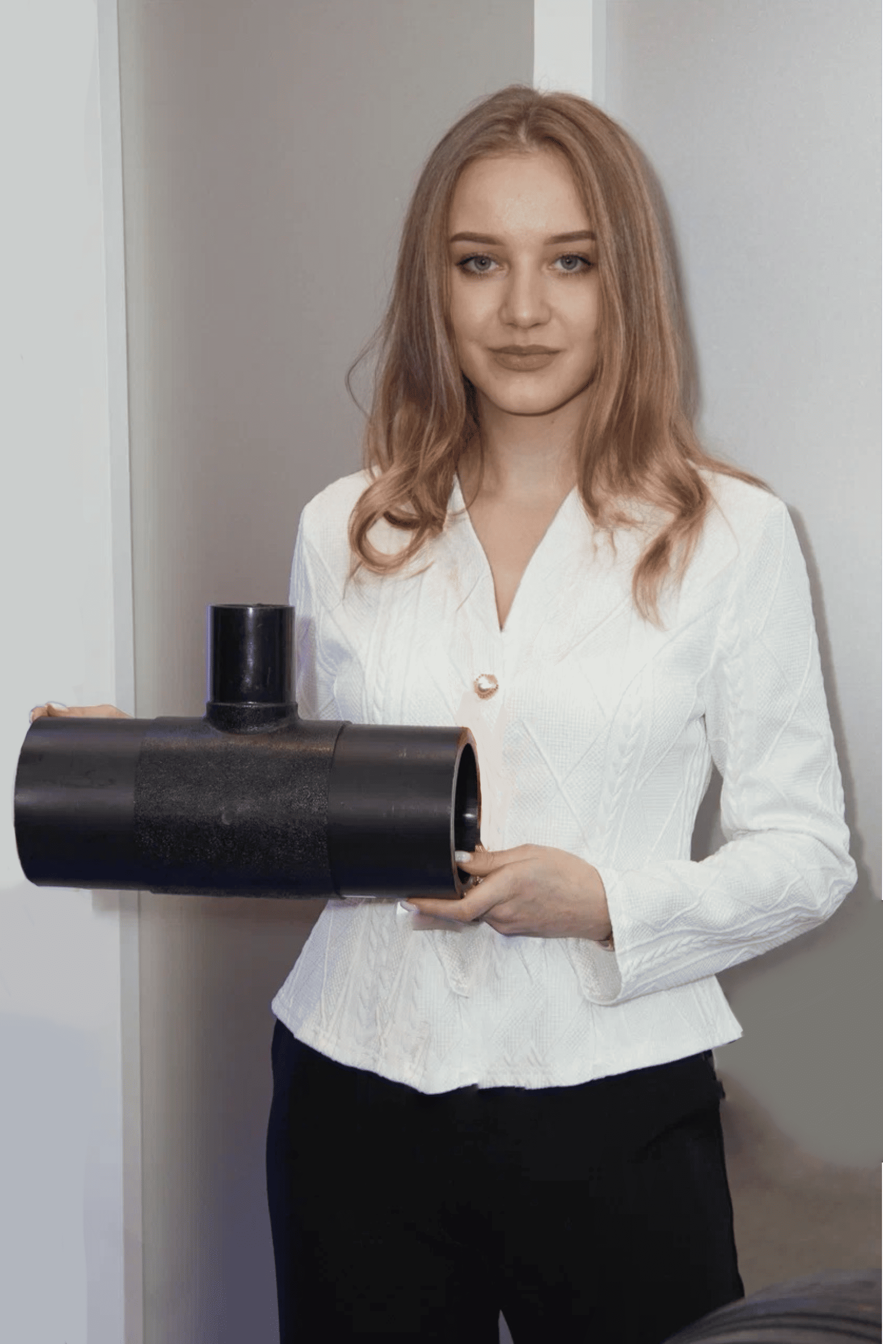 Девушка в светлом жакете держит в руках литой тройник ПНД бренда GQ