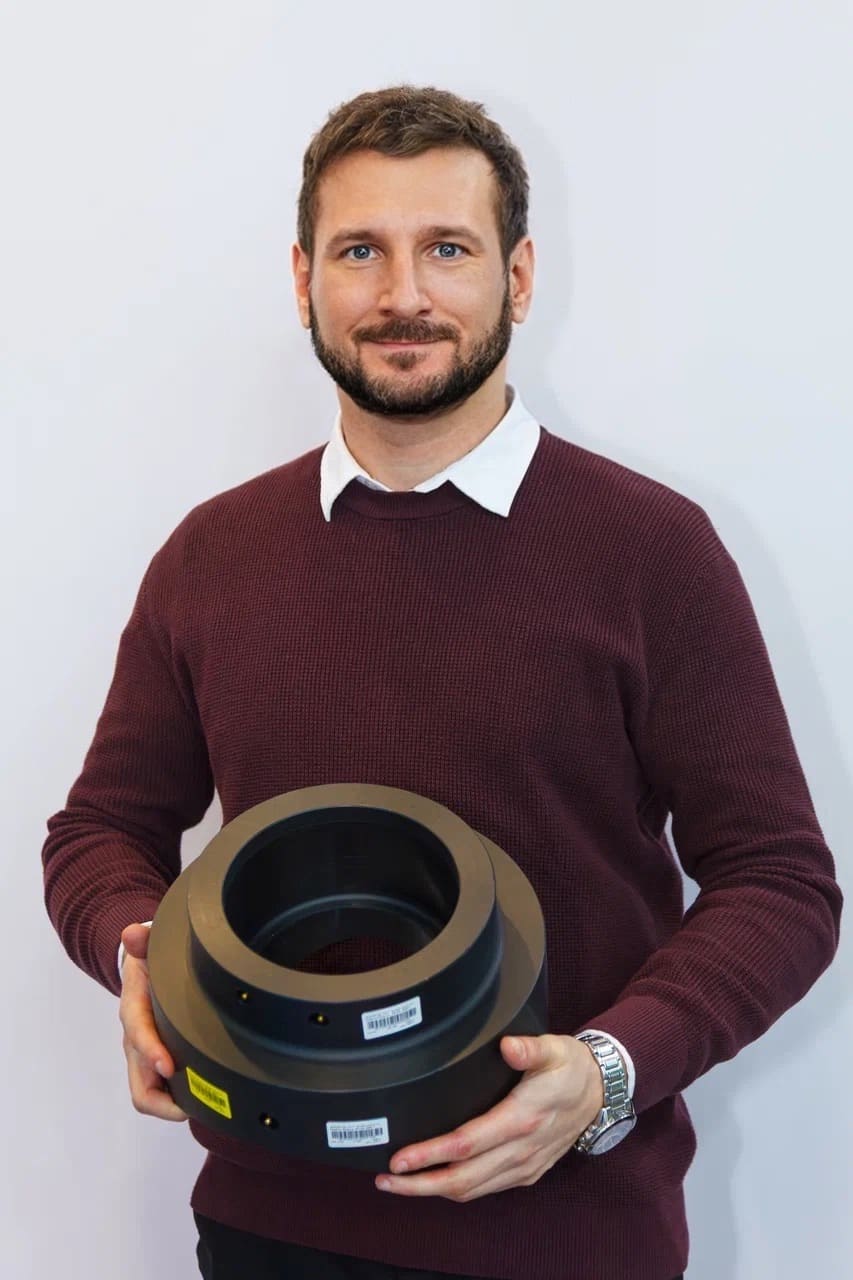 Мужчина в бордовом свитере держит в руках седелку ПНД бренда Smart Joint